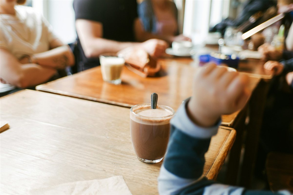 カフェの木製テーブルを囲んで打ち合わせをする人々のイメージ