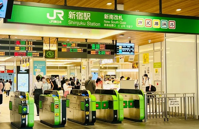 JR新宿駅新南改札の看板と緑色の自動改札機が並ぶ構内、行き交う乗降客の様子