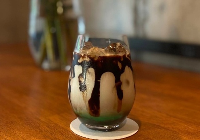木のテーブルに置かれたアイスコーヒー、層になった見た目のドリンク