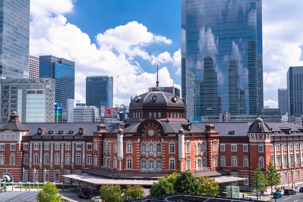 青空を背景にそびえる東京駅丸の内駅舎の赤レンガ建物と高層ビル群